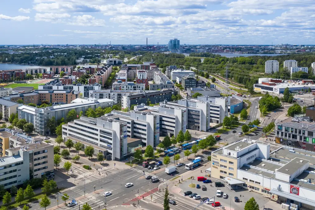 Usean toimitilakiinteistön muodostama kokonaisuus Opus Business Park kuvattuna ilmasta. Kiinteistöjen edessä kulkee autotie, ja taustalla kaupunki näkymää.