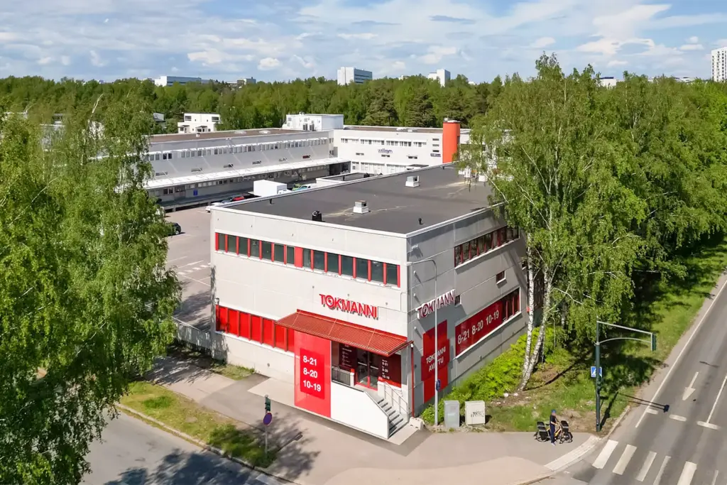 Helsingin Sirrikuja 1 -kiinteistö tien kulmassa. Pihassa lastauslaiturit ja pysäköintitilaa, kulmasta sisäänkäynti Tokmanniin.