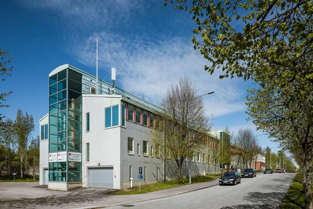 Helsingin Rälssintie 10-kiinteistön harmaa julkisivu ja rakennuksen päädyssä ikkunoilla ympäröity portaikko.