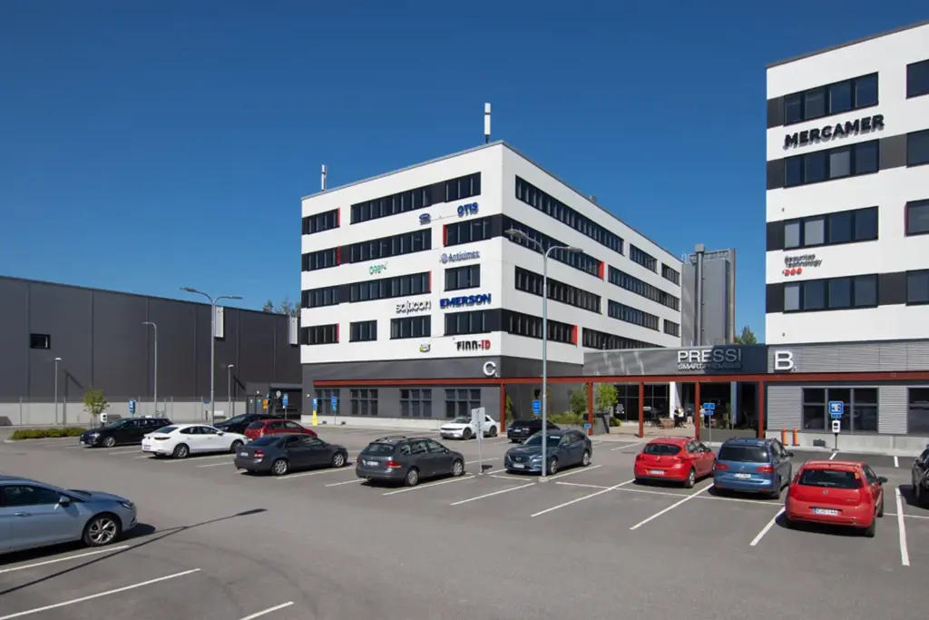 PRESSI Smart Premises C-talon julkisivu. Valkoinen, moderni 5-kerroksinen toimitilakiinteistö, jonka edessä on pysäköintialue.